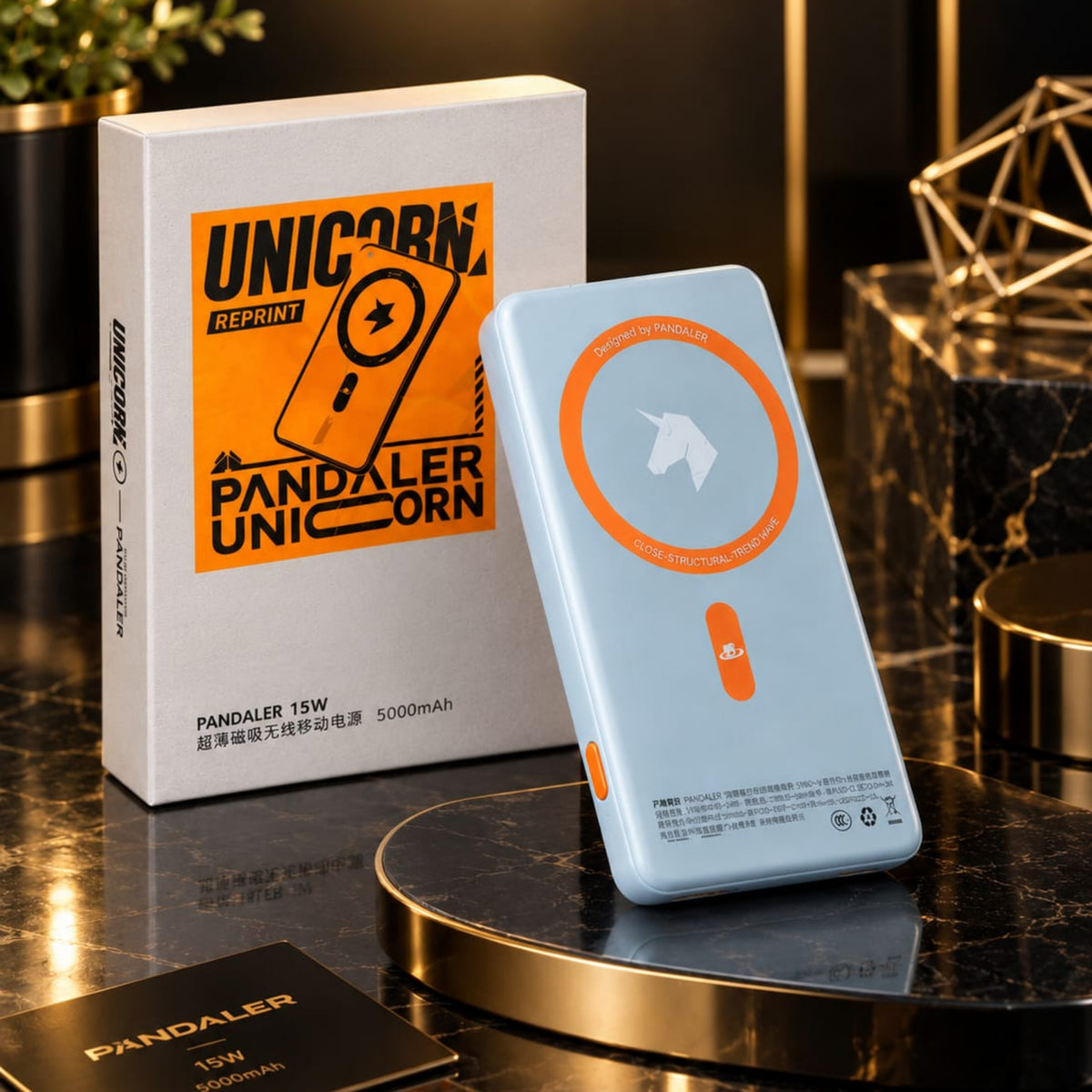 A light blue Pandaler Unicorn 15W portable power bank standing upright next to its white and orange retail box on a dark marble display surface with gold accents.