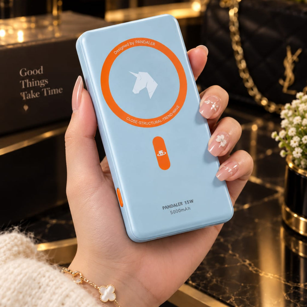 A hand holding a light blue power bank with an orange circular magnetic charging indicator and a unicorn logo, set against a luxurious dark marble and gold background.