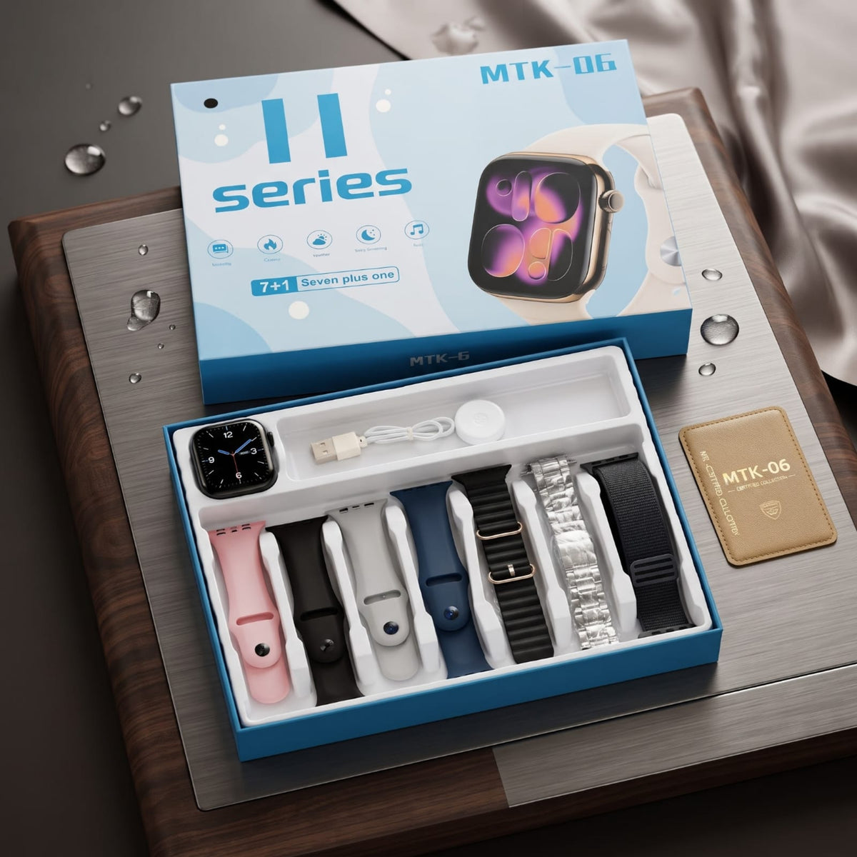 MTK-06 Apple Watch 7 Plus One watch band set in a blue and white box, displayed open with six different watch straps (pink, black, white, navy, silver, and black) alongside the retail packaging and a gold card on a wooden tray.