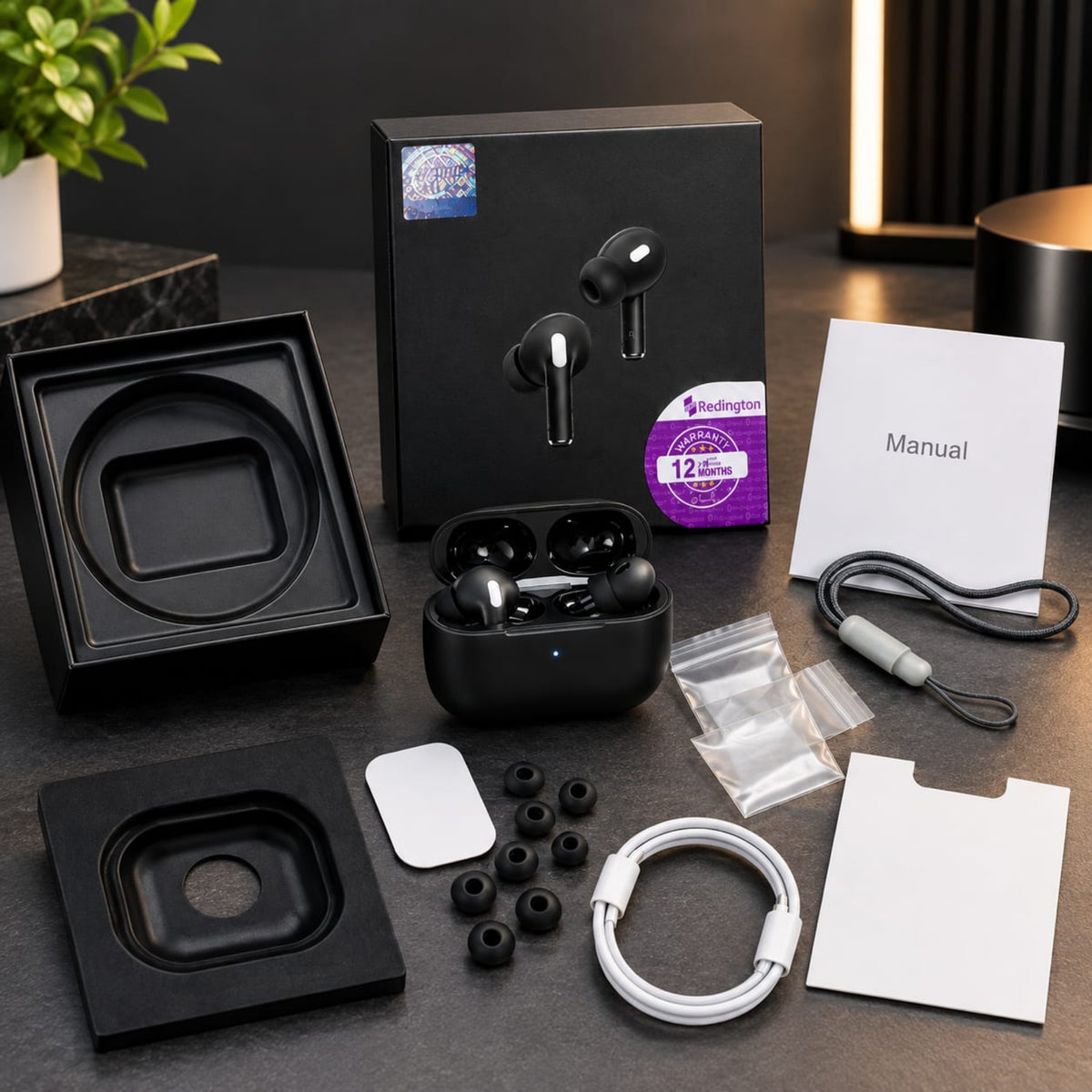 Black wireless earbuds with their charging case and accessories arranged on a dark tabletop, including the retail box, manual, cable, ear tips, and protective inserts.
