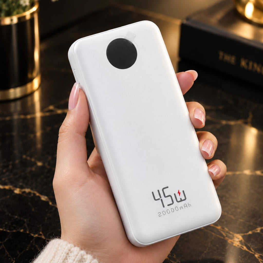 A hand holding a white 45W 20000mAh portable power bank with a circular camera-style cutout on the back, set against a dark marble tabletop background.