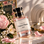 A 50ml bottle of Gucci Flora perfume with a black cap and gold accents, set on a marble surface surrounded by pink peonies, white flowers, and soft sunlight.